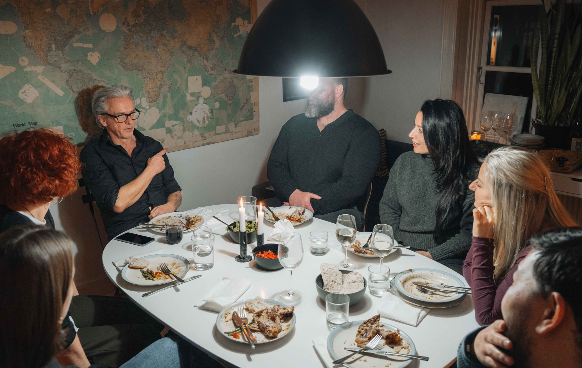Guests and a local host in conversation around a candlelit dinner table